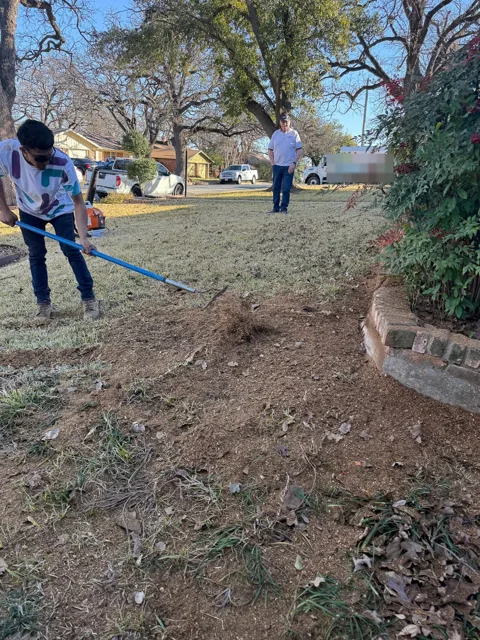 Crew member raking chips into a clean yard after the job